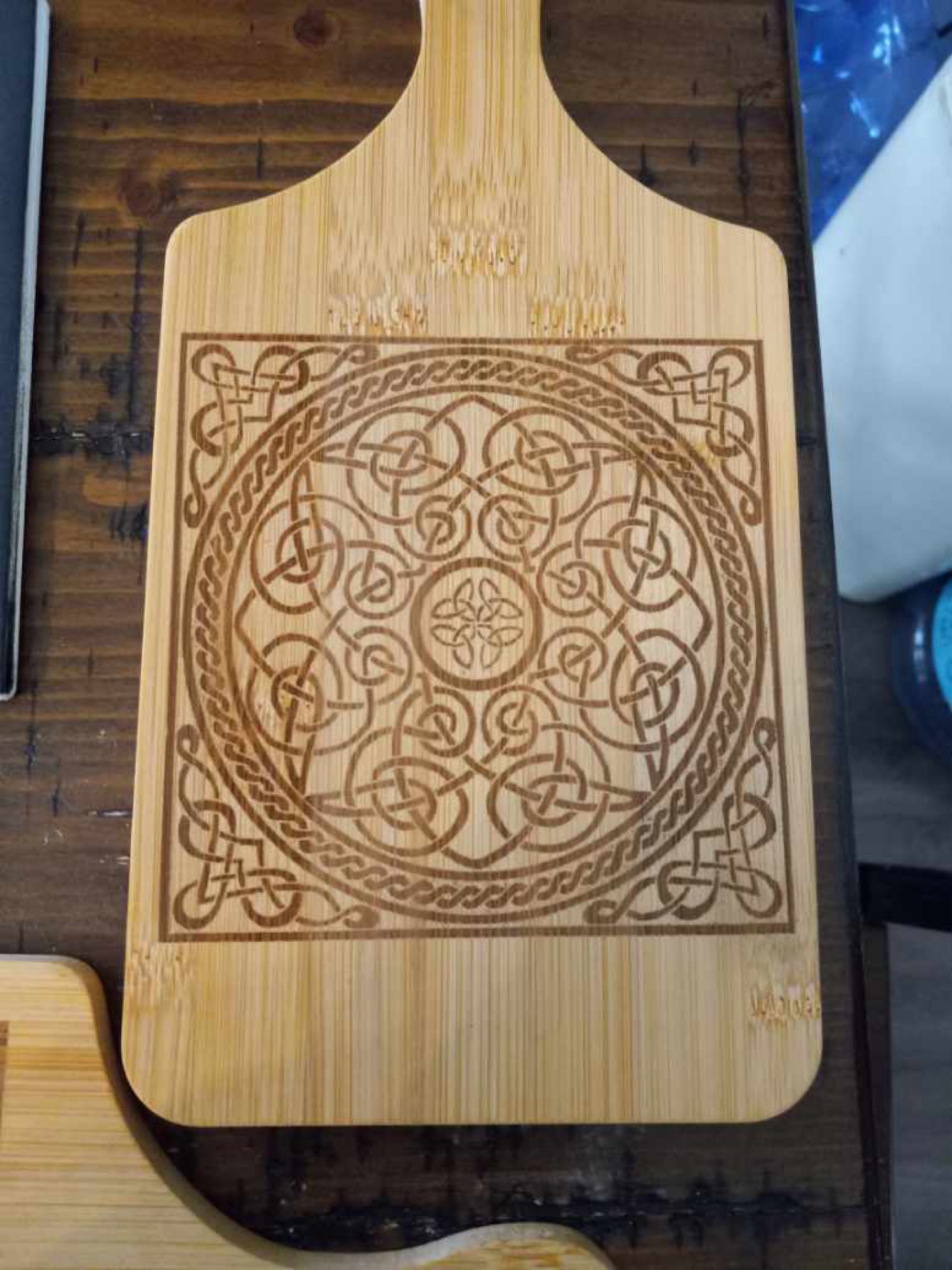 Close-up of intricate Celtic knotwork laser engraved on a bamboo cutting board