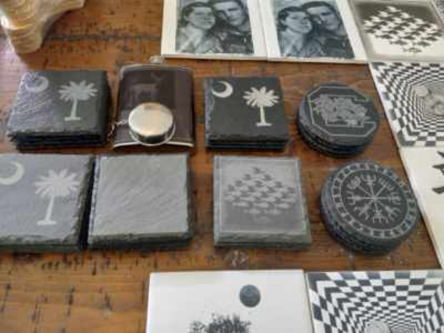Table display of slate coasters, flask, and engraved tiles