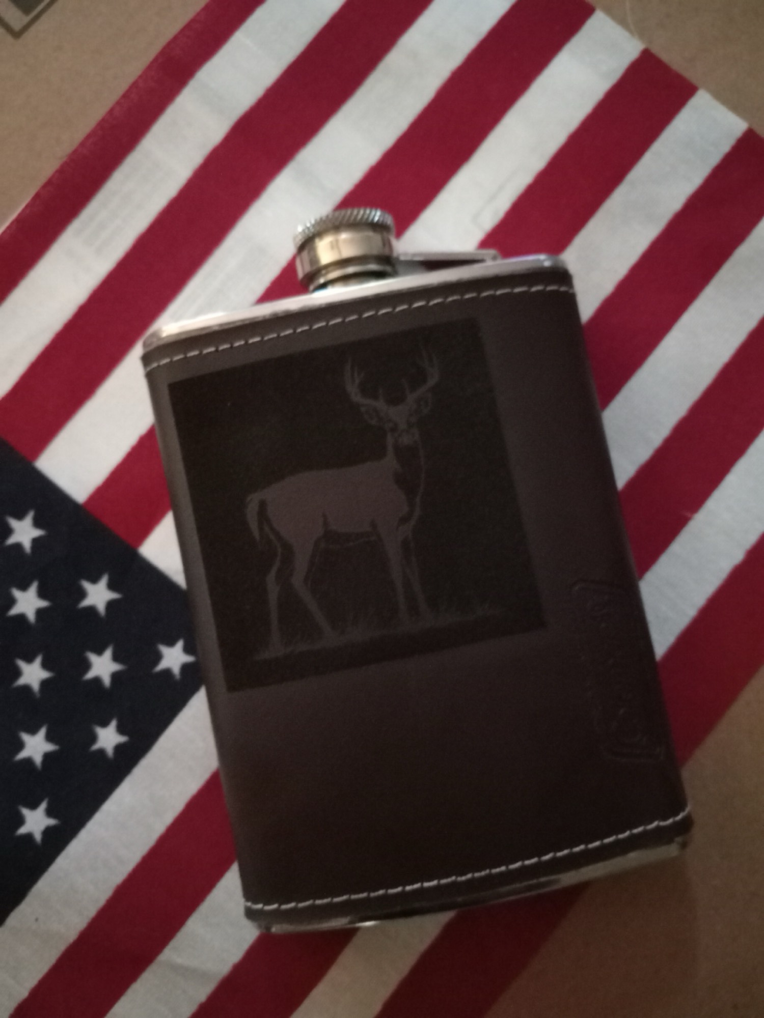 Leather-wrapped flask with engraved deer standing against an American flag background